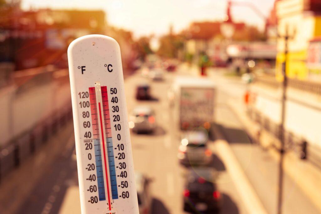 Thermometer vor Autos und Verkehr während einer Hitzewelle