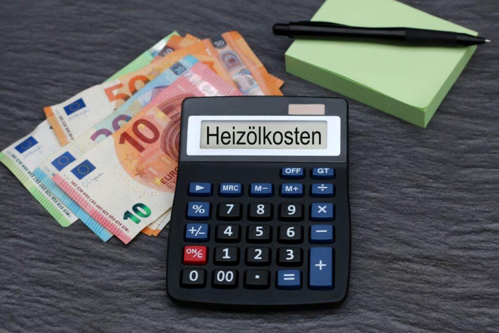 Taschenrechner mit dem Wort Heizölkosten, daneben Euro-Geldscheine – Symbolbild für steigende Heizölpreise NRW